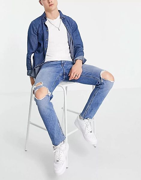 ASOS DESIGN – Schmal geschnittene Jeans mit Knierissen und unbehandeltem Sa günstig online kaufen